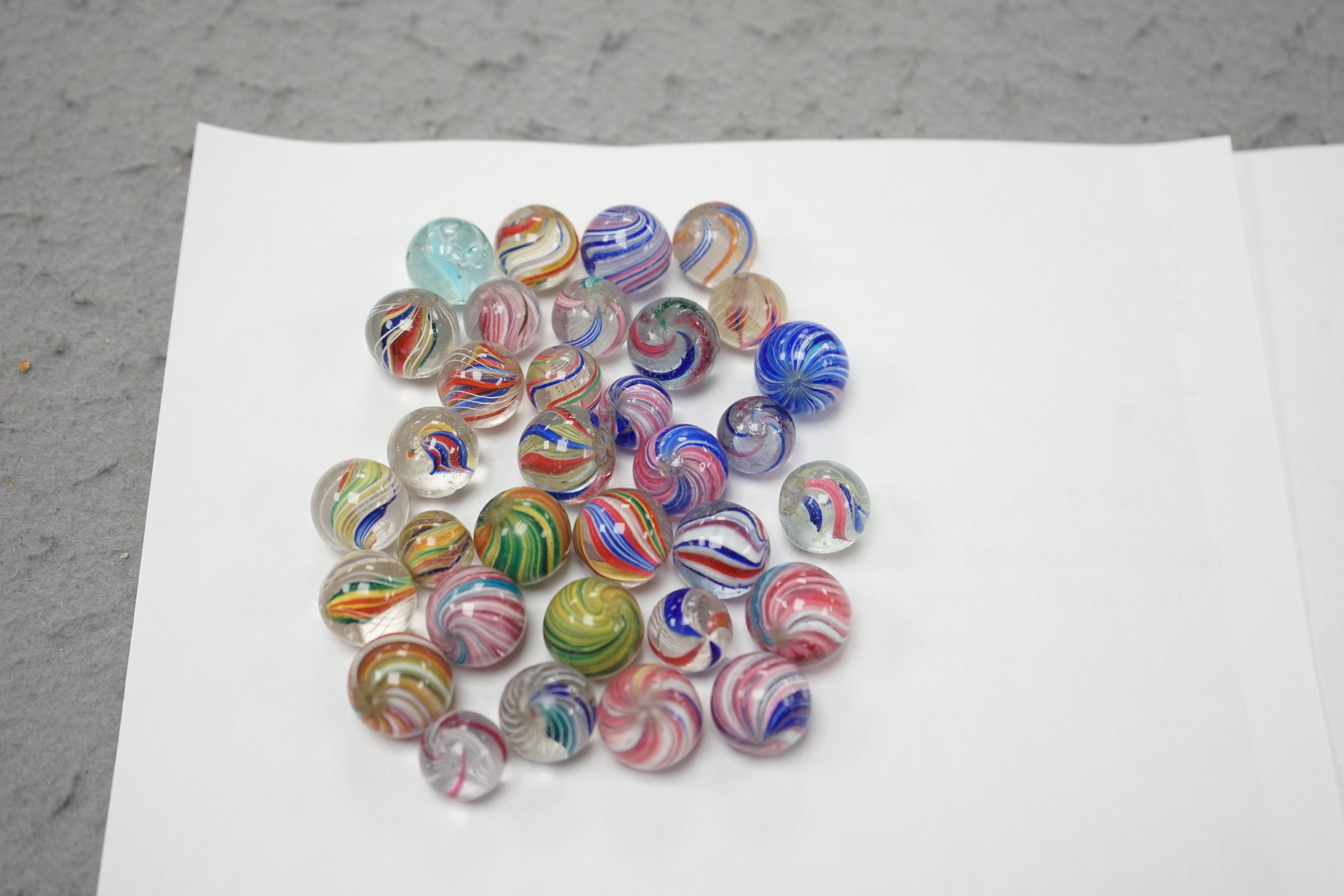 A mahogany solitaire board with a collection of latticino and marbled glass marbles